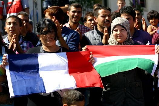 TURKEY, Istanbul: Refugees hold up a French and Italian flag as they wait near the Esenler Bus Terminal in Istanbul, Turkey on September 19, 2015 after the government ordered that bus tickets not be sold to them. They are waiting for the government to reverse their decision so they can travel to the Turkish border town of Edirne to continue their journey into Europe