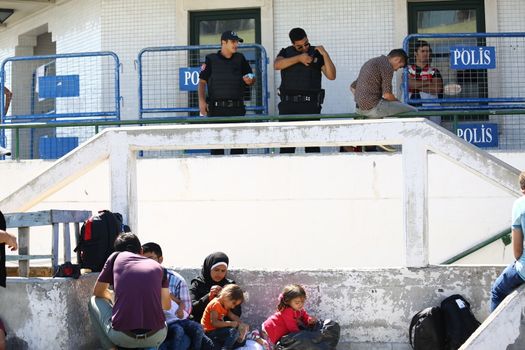 TURKEY, Istanbul: Police watch the crowd of refugees from a police station near the Esenler Bus Terminal in Istanbul, Turkey on September 19, 2015 after the government ordered that bus tickets not be sold to refugees. They are waiting for the government to reverse the decision so they can travel to the Turkish border town of Edirne to continue their journey into Europe