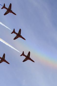 ENGLAND, Southport: Red Arrows fly in formation leaving coloured smoke trails while a rainbow appears in the background during the Southport Airshow 2015 in Southport, Merseyside in England on September 19, 2015