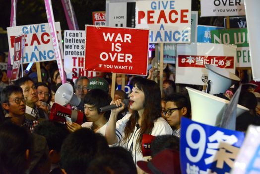 JAPAN, Tokyo: Protestors hold signs near Japanese parliament in Tokyo, Japan, on September 15, 2015 during a demonstration against security law. Demonstrators claim Japanese Prime minister Shinzo Abe's resignation.