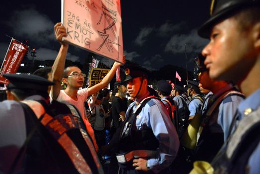 JAPAN, Tokyo: A protestor holds a sign in front of police officers near Japanese parliament in Tokyo, Japan, on September 14, 2015 during a demonstration against security law. Demonstrators claim Japanese Prime minister Shinzo Abe's resignation.