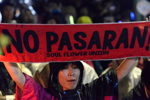 JAPAN, Tokyo: A protestor holds a sign which reads No Pasaran near Japanese parliament in Tokyo, Japan, on September 17, 2015 during a demonstration against security law. Demonstrators claim Japanese Prime minister Shinzo Abe's resignation.