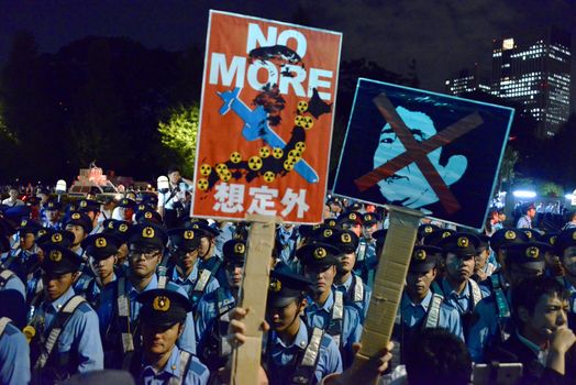JAPAN, Tokyo: Demonstrators hold signs in front of police officers near Japanese parliament in Tokyo, Japan, on September 15, 2015 during a demonstration against security law. Demonstrators claim Japanese Prime minister Shinzo Abe's resignation.