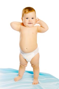 Funny baby in diaper standing on a blue blanket. Studio. Isolated