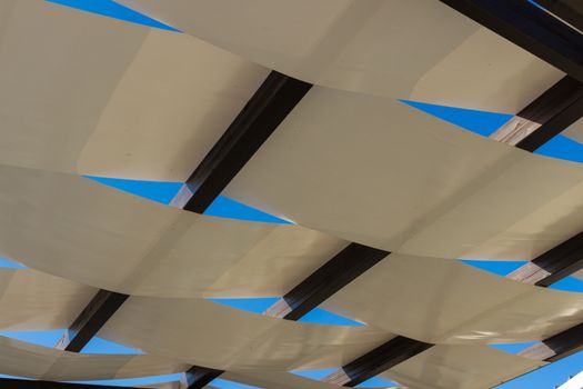 Detail of white pergola roof and blue sky.