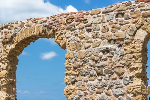 Stone gate with sky view at Cefalu Sicily promenade.