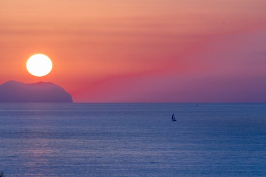 Sunset at sea with shipping boat silhouette.