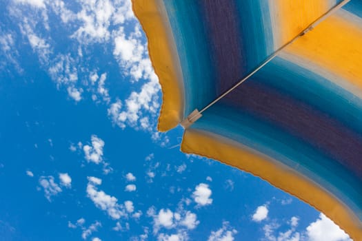 Colorful beach umbrella on a sunny summer day. Copy space.