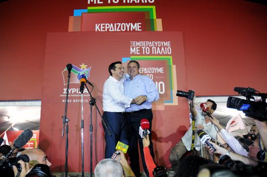 GREECE, Athens: Syriza leader Alexis Tsipras (left) embraces leader of the Independent Greeks party Panos Kammenos while addressing supporters in Athens after claiming victory in Greece's parliamentary election on September 20, 2015. The two parties plan to form a coalition government after the leftist Syriza defeated its main rival, the conservative New Democracy party, with an early figure of 35.46 per cent of the vote. 
