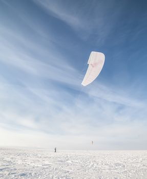 Kite surfer being pulled by his kite across the snow