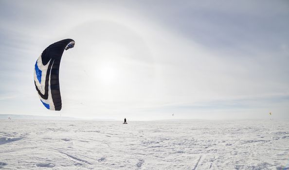 Kite surfer being pulled by his kite across the snow