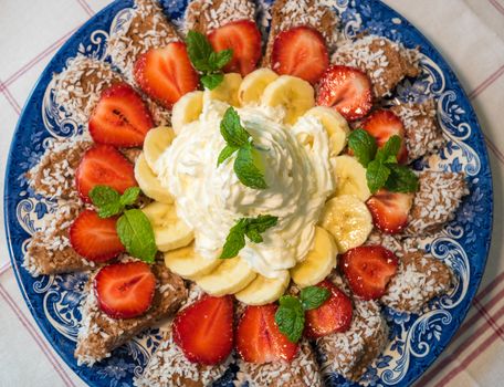 Chocolate dessert with banana, strawberry and mint under whipped cream