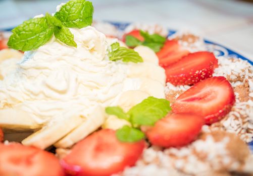 Chocolate dessert with banana, strawberry and mint under whipped cream