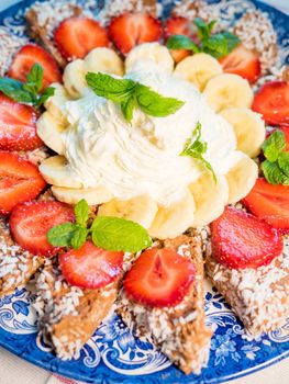 Chocolate dessert with banana, strawberry and mint under whipped cream