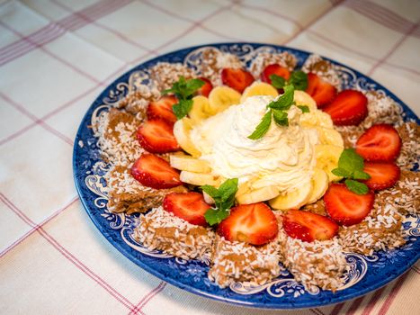 Chocolate dessert with banana, strawberry and mint under whipped cream