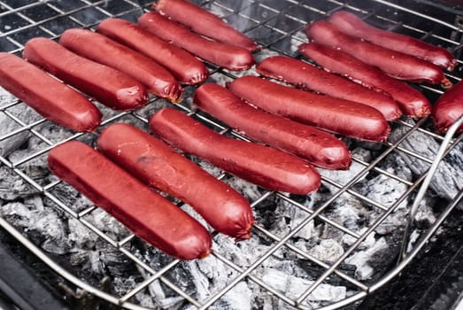 Photograph of some red pork sausages at a hot gril
