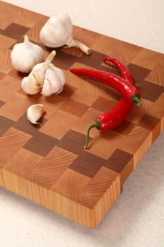 segment of garlic and two chili peppers on a chopping board