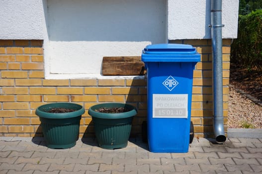 POZNAN, POLAND - JULY 18, 2015: Blue plastic trash container against a wall