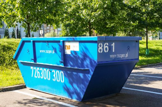 POZNAN, POLAND - JULY 02, 2015: Blue trash container on a parking lot spot 
