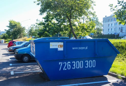 POZNAN, POLAND - JULY 02, 2015: Blue trash container on a parking lot spot 