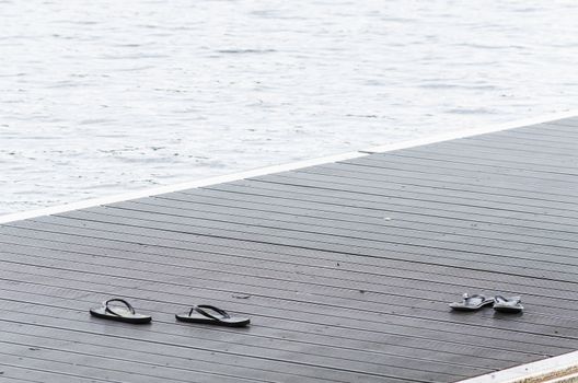 Black sandals on a boat dock on a promenade along the lake.