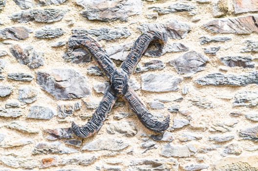 Old castle stone wall with the letter X made of wrought iron. texture background.
