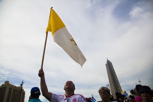 CUBA, Havana: A man holds a Vatican flag as Pope Francis performs mass in Revolution Square in Havana, on September 20, 2015. Pope Francis is on the first full day of his three day visit to Cuba, where he meets President Raul Castro and Fidel Castro and hold Mass in Revolution Square before travelling to Holguin, Santiago de Cuba and El Cobre, then onwards to the United States.