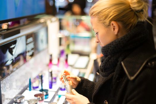 Beautiful blond lady testing  and buying cosmetics in a beauty store. 