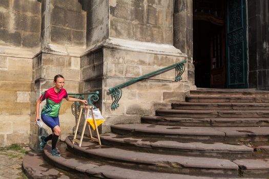 Woman punching at control point, taking part in orienteering city race competitions in old european city