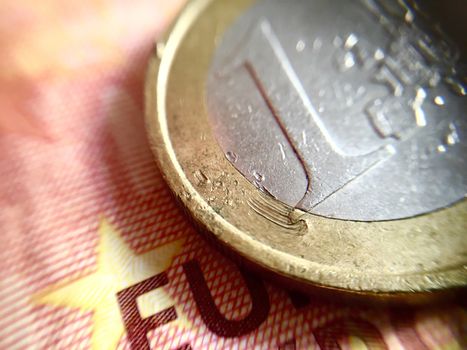 Close up of a scratched 1€ coin over a 10€ banknote