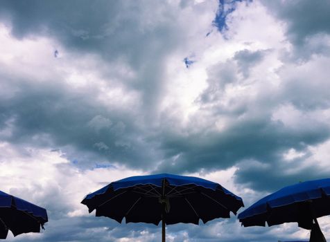 Umbrelllas opened with a sky threatening rain behind in an italian beach in september