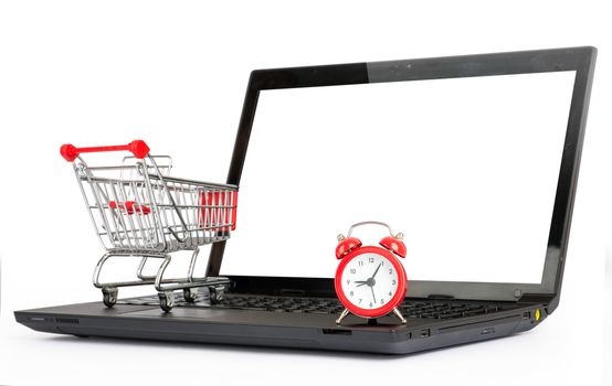 Shopping cart and alarm clock on laptop on isolated white background, close up view