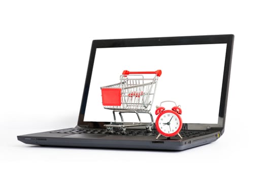Shopping cart and alarm clock on laptop on isolated white background, close up view