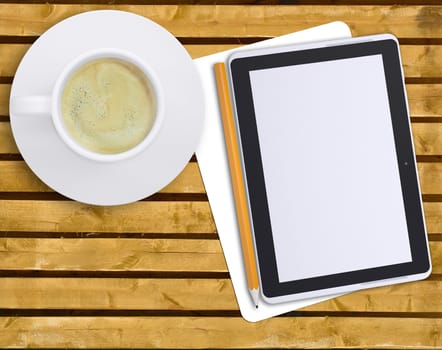 Tablet with cup of coffee and pencil on wooden table