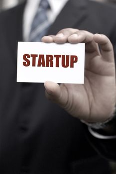 Business man holding out a card with startup