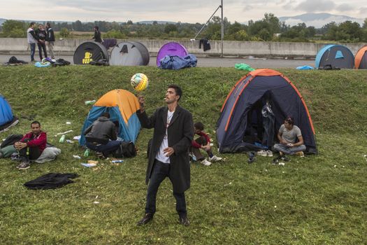 CROATIA, Harmica: One man smokes and plays soccer as refugees on the border between Croatia and Slovenia find ways to pass the time on September 20, 2015.  Refugees are at the mercy of European authorities as they attempt to escape their war-ravaged countries.