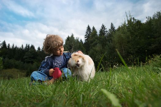 Cute little boy cuddling his dog in nature