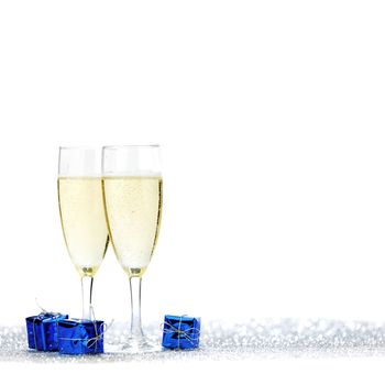 Glasses of champagne and blue gifts isolated on white