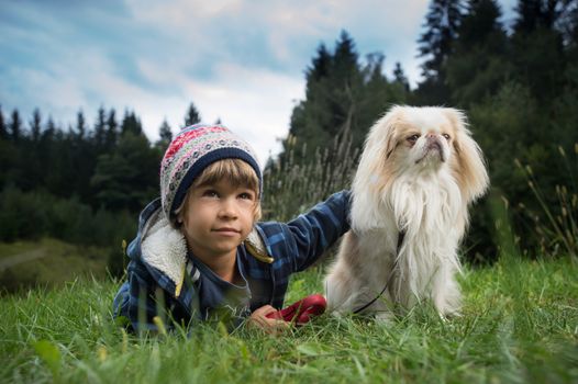 Cute little boy lying on the grass next to his dog. Best friends concept.