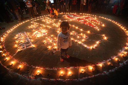 NEPAL, Kathmandu: A child is surrounded with candles at a celebration in Kathmandu, Nepal on September 21, 2015, one day after the government unveiled the country's first democratic constitution in a historic step. Out of the 598 members of the Constituent Assembly, 507 voted for the new constitution, 25 voted against, and 66 abstained in a vote on September 16, 2015. The event was marked with fireworks and festivities, but also with protests organized by parties of the Tharu and Madhesi ethnic communities.Photos taken by Newzulu contributor Dinesh Shrestha show the Nepalese people lighting candles to mark new chapter in the history of their country.