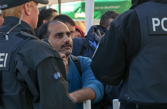 GERMANY, Passau: Security officials talk with a refugee waiting in long queues in the border town of Passau, Germany on September 21, 2015 amid the reintroduction of border controls in Germany, Austria, and a number of other EU countries, aimed at slowing the flow of refugees from war-torn Syria.