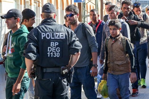 GERMANY, Passau: Security officials stand guard as refugees wait in long queues in the border town of Passau, Germany on September 21, 2015 amid the reintroduction of border controls in Germany, Austria, and a number of other EU countries, aimed at slowing the flow of refugees from war-torn Syria.
