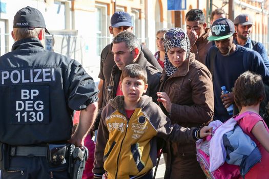 GERMANY, Passau: Security officials stand guard as refugees wait in long queues in the border town of Passau, Germany on September 21, 2015 amid the reintroduction of border controls in Germany, Austria, and a number of other EU countries, aimed at slowing the flow of refugees from war-torn Syria.