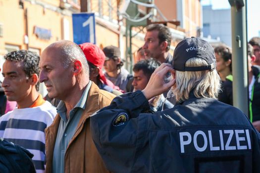 GERMANY, Passau: Security officials stand guard as refugees wait in long queues in the border town of Passau, Germany on September 21, 2015 amid the reintroduction of border controls in Germany, Austria, and a number of other EU countries, aimed at slowing the flow of refugees from war-torn Syria.