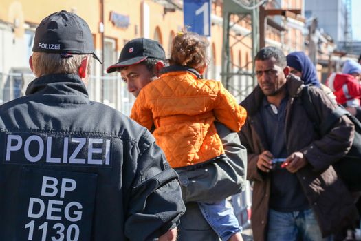 GERMANY, Passau: Security officials stand guard as refugees wait in long queues in the border town of Passau, Germany on September 21, 2015 amid the reintroduction of border controls in Germany, Austria, and a number of other EU countries, aimed at slowing the flow of refugees from war-torn Syria.