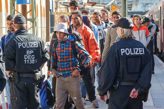 GERMANY, Passau: Security officials stand guard as refugees wait in long queues in the border town of Passau, Germany on September 21, 2015 amid the reintroduction of border controls in Germany, Austria, and a number of other EU countries, aimed at slowing the flow of refugees from war-torn Syria.