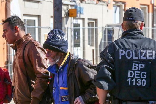 GERMANY, Passau: Security officials stand guard as refugees wait in long queues in the border town of Passau, Germany on September 21, 2015 amid the reintroduction of border controls in Germany, Austria, and a number of other EU countries, aimed at slowing the flow of refugees from war-torn Syria.