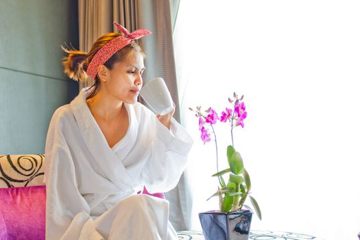 Lady wearing nightgown and drinking coffee in the morning