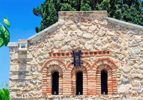 Detail of the facade of the ancient chapel of natural stone with three narrow Windows on the island of Crete, Greece