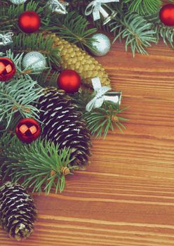 Corner Border of Spruce Branch and Fir Cones with Hoarfrost, Red and Silver Baubles, Bows closeup on Wooden background